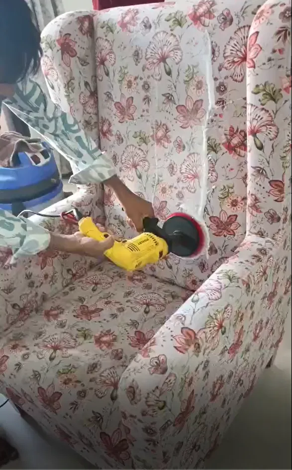 Drill-brush scrubbing a fabric armchair during professional sofa cleaning in Silvassa